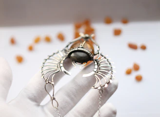 Close-up of a hand holding a glowing semi-precious gemstone bracelet against a soft pastel background.