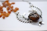 A close-up of a handcrafted necklace featuring intricate wire wrapping with a polished amber stone.
