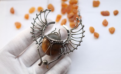 A moth-shaped pendant glowing softly against a dark velvet background.