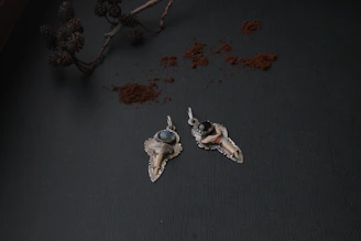 Silver pendant shaped like a mountain range resting on a bed of pine needles.