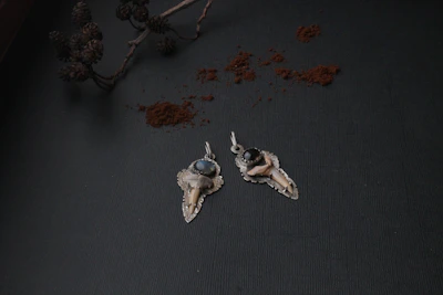 Elegant silver pendant featuring a baby's tooth sealed in resin, displayed on a soft blush pink background.