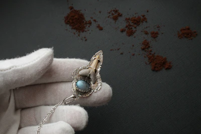 Gloved hands holding a gold ingot against a dark, elegant background.
