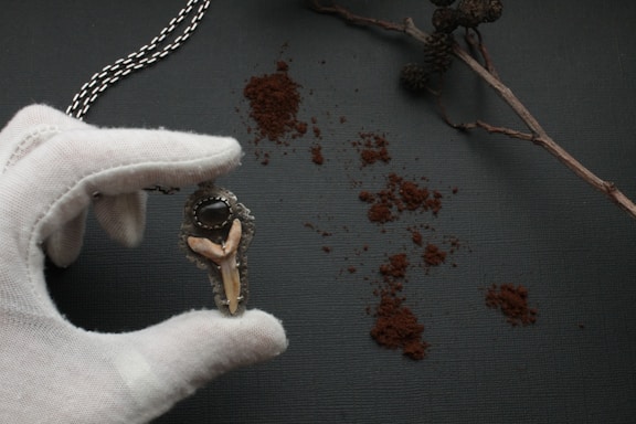 A close-up of a custom corrupted eye pendant glowing softly on a velvet cushion.