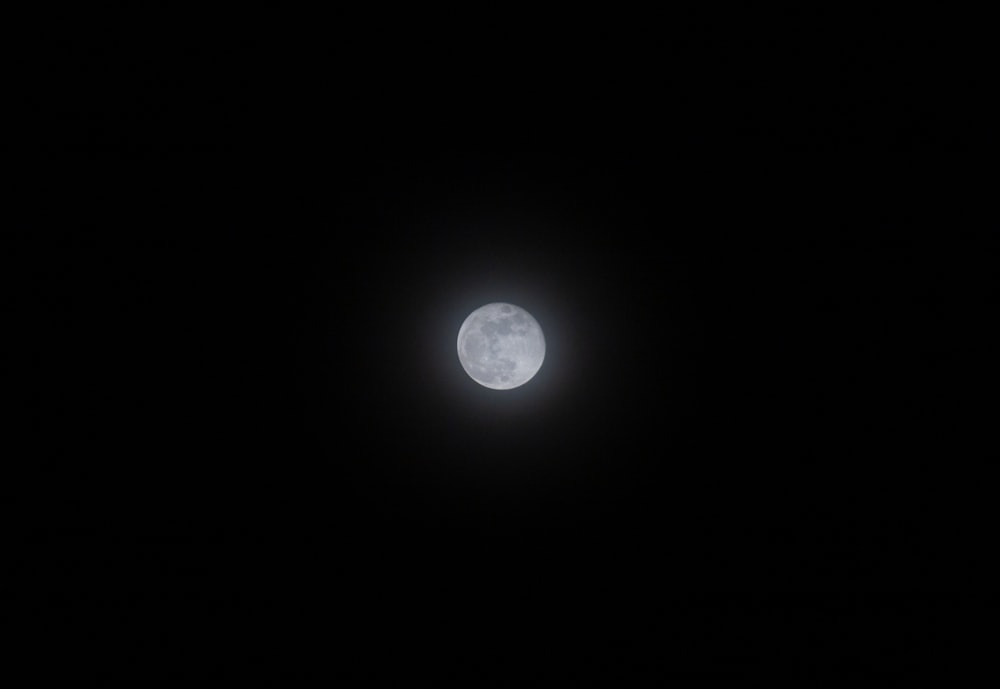 a full moon is seen in the dark sky