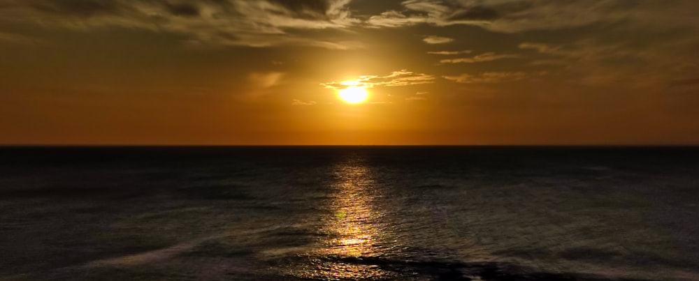 O sol está se pondo sobre o oceano em um dia nublado