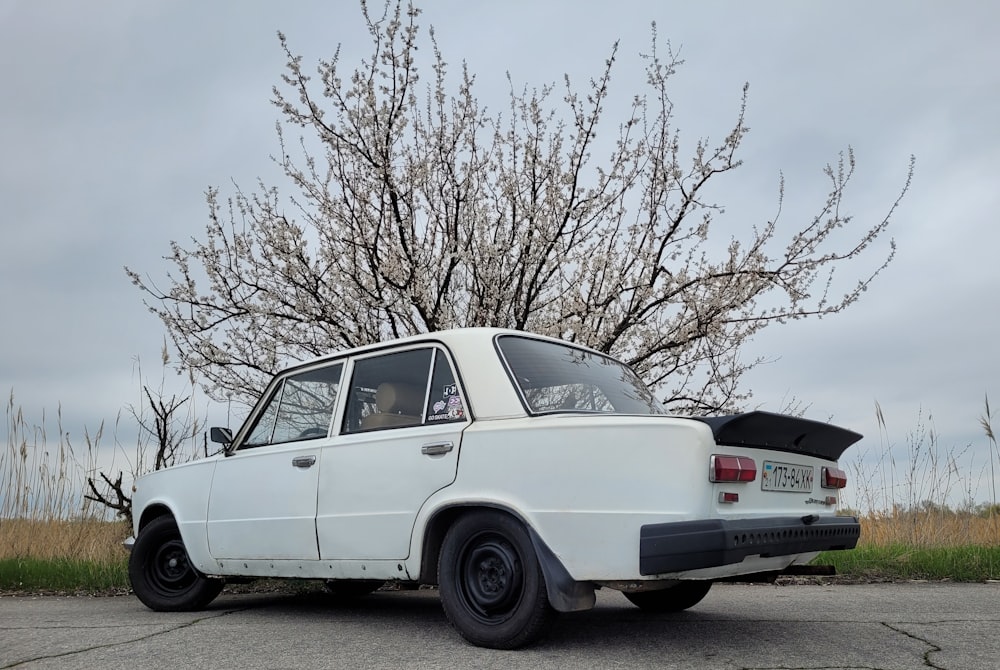 an old white car parked in front of a tree