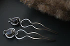 Assorted hair accessories in black and gold tones arranged artfully on a nude-toned background