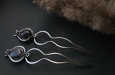 Delicate gold-accented hair claws resting on a white surface with rose red accents.