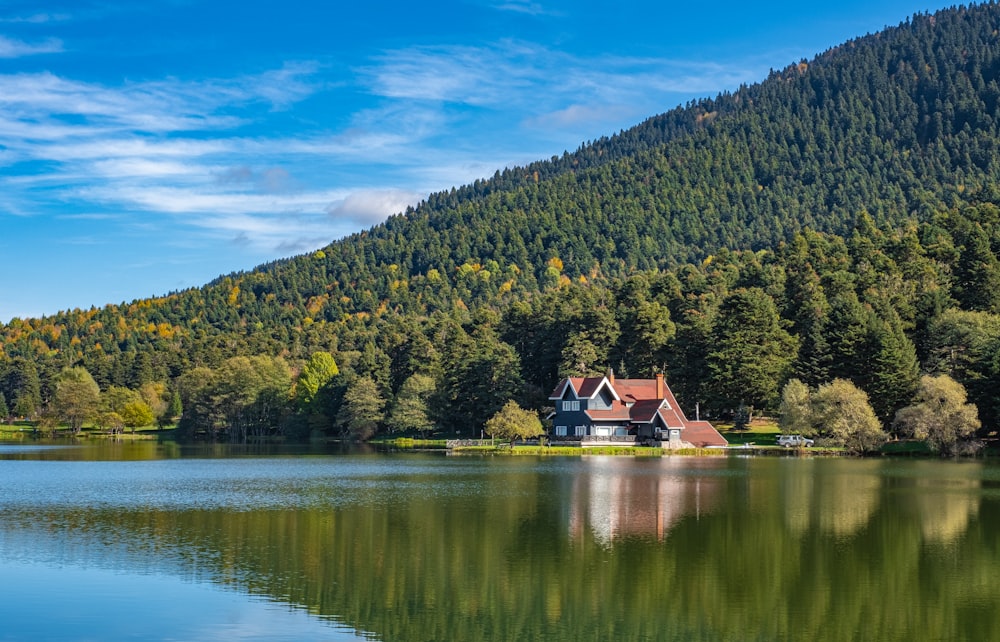uma casa sentada no topo de um lago ao lado de uma floresta
