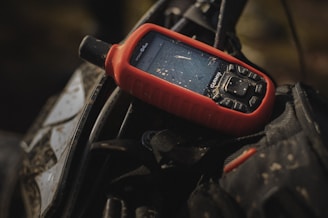 a red cell phone sitting on top of a black bag