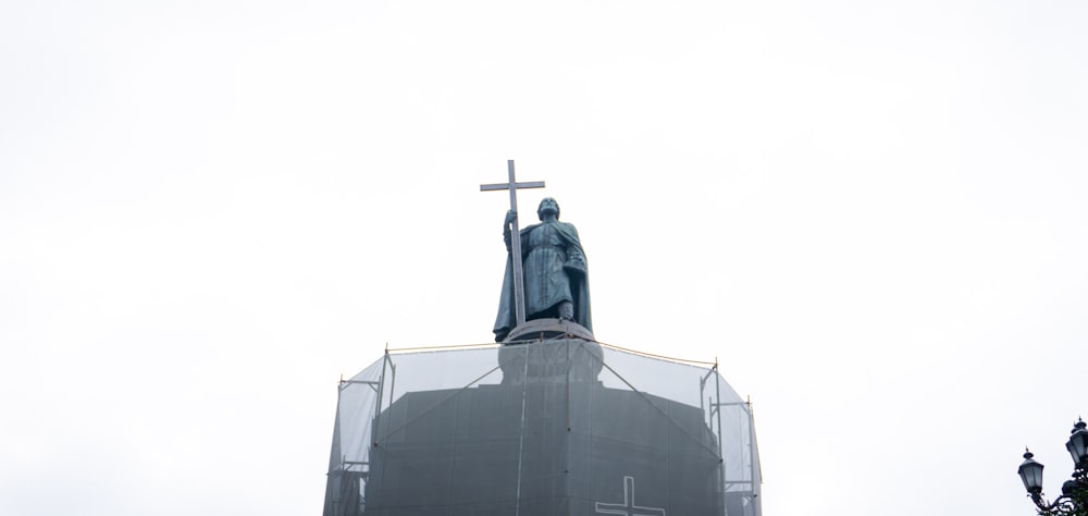 a statue of a person with a cross on top of a building