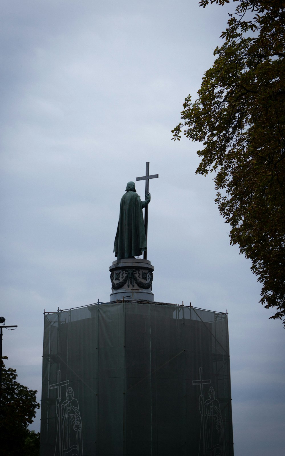 a statue of a man holding a cross on top of a building