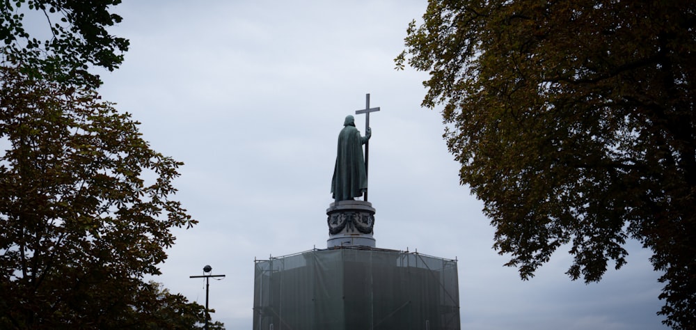 eine Statue einer Person, die ein Kreuz auf dem Dach eines Gebäudes hält