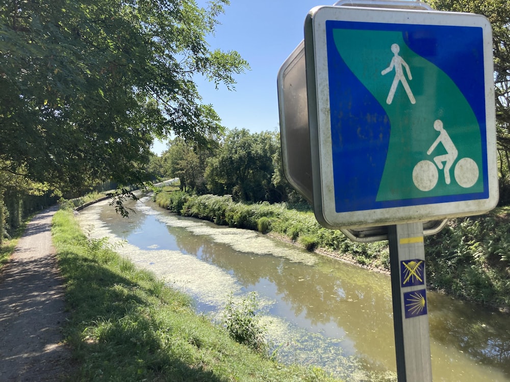 a blue and white sign on a pole next to a river