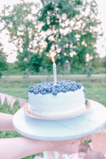 Close-up of a beautifully decorated birthday cake on the yacht deck with turquoise sea in the background.