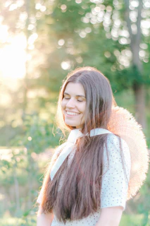 A smiling woman wearing a delicate ribbon in her hair, sunlight highlighting the texture.