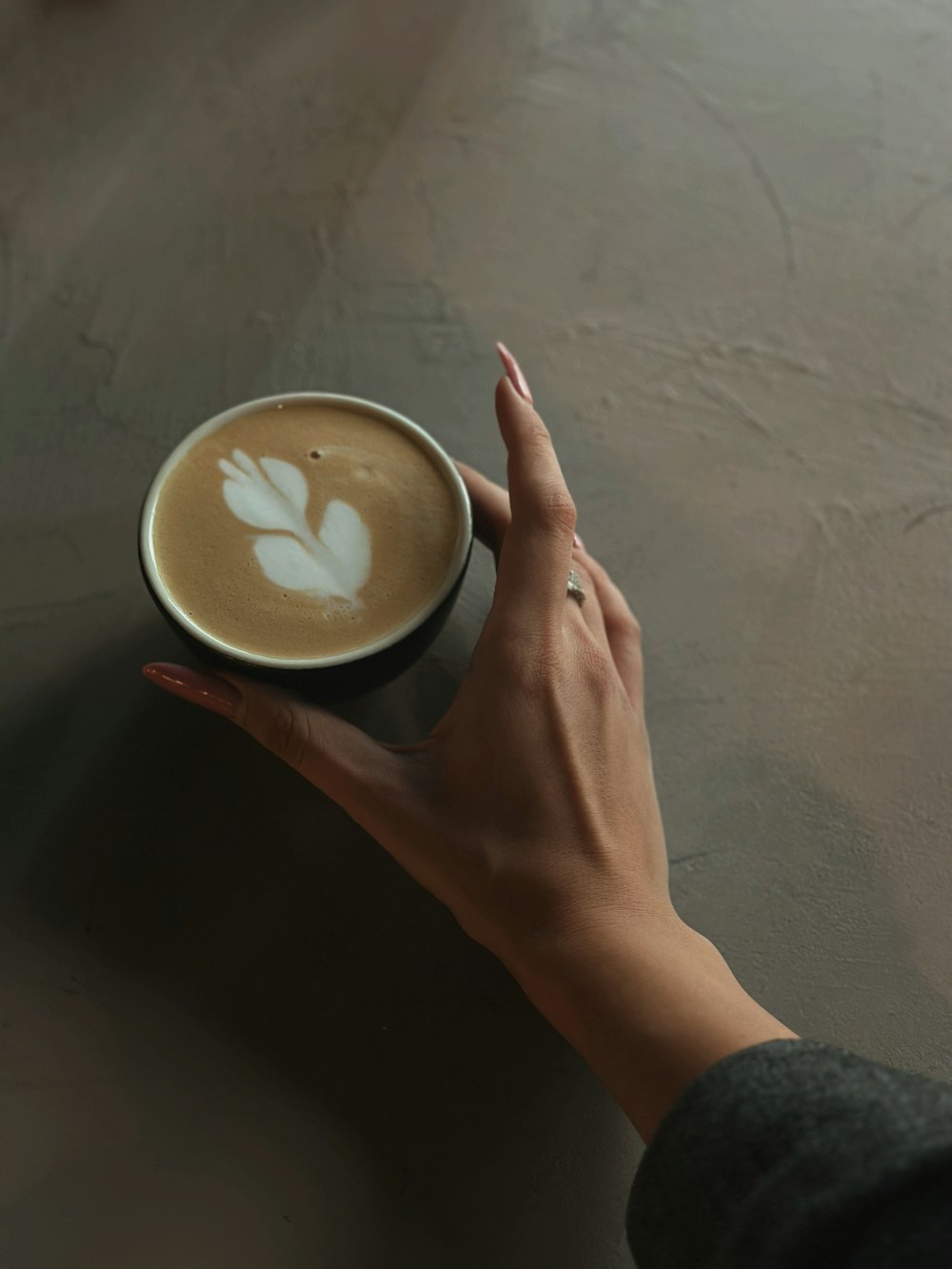 la mano de una mujer sosteniendo una taza de café