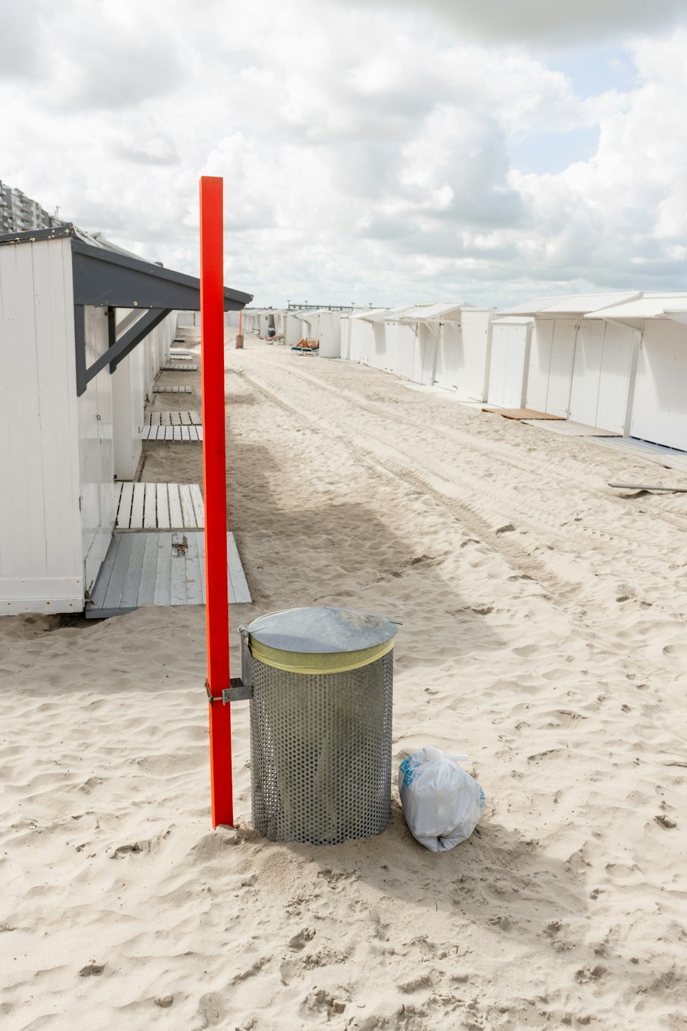 a trash can sitting on top of a sandy beach