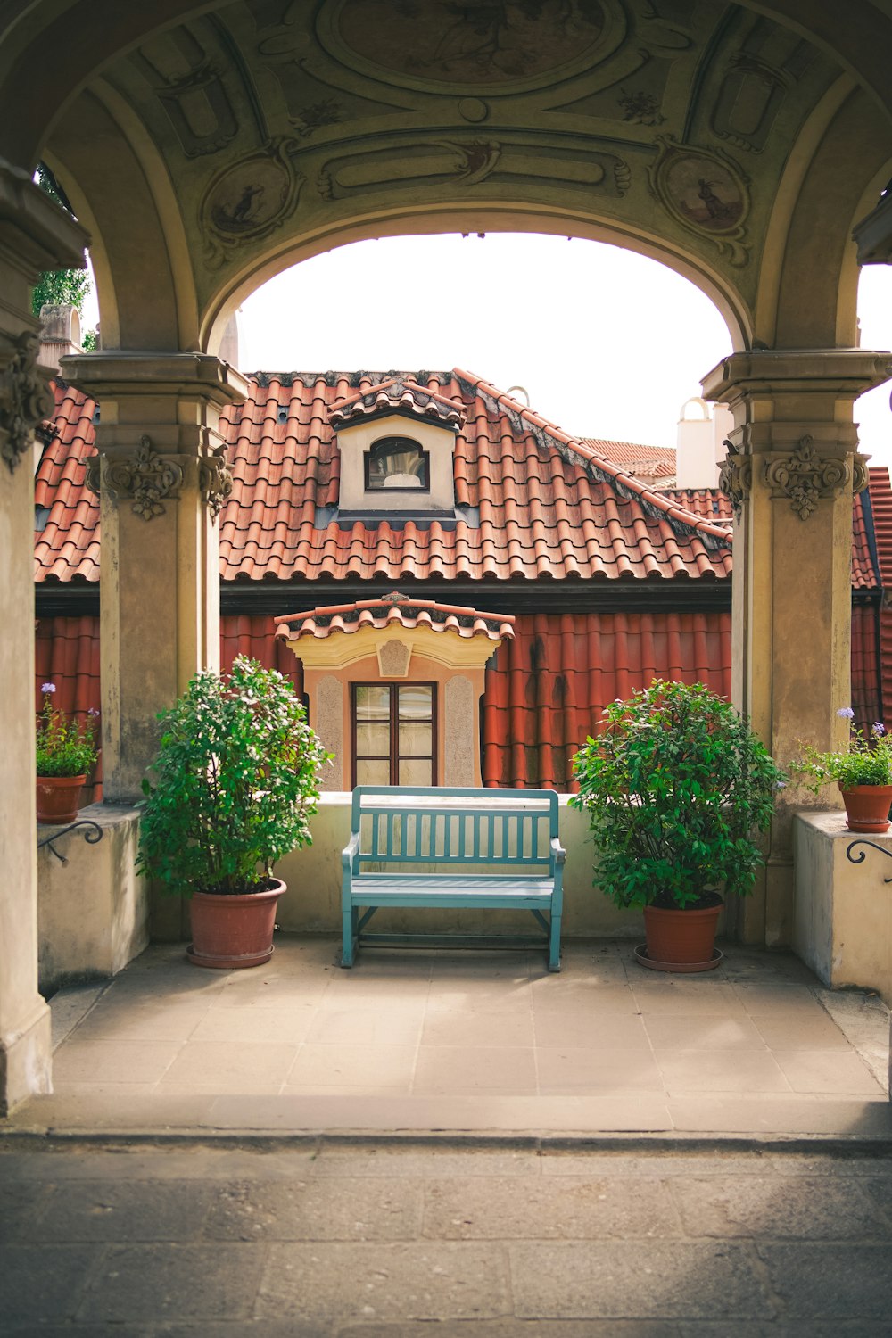 a blue bench sitting under an archway next to potted plants