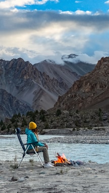 A cozy camping scene with someone wearing a waterproof jacket beside a tent in light rain.
