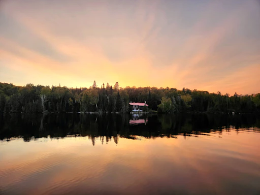 A cozy guest house nestled by the calm waters of Lake Toba at sunset.