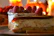 Close-up of a perfectly plated slice of rich cheesecake with golden crust and raspberry drizzle.