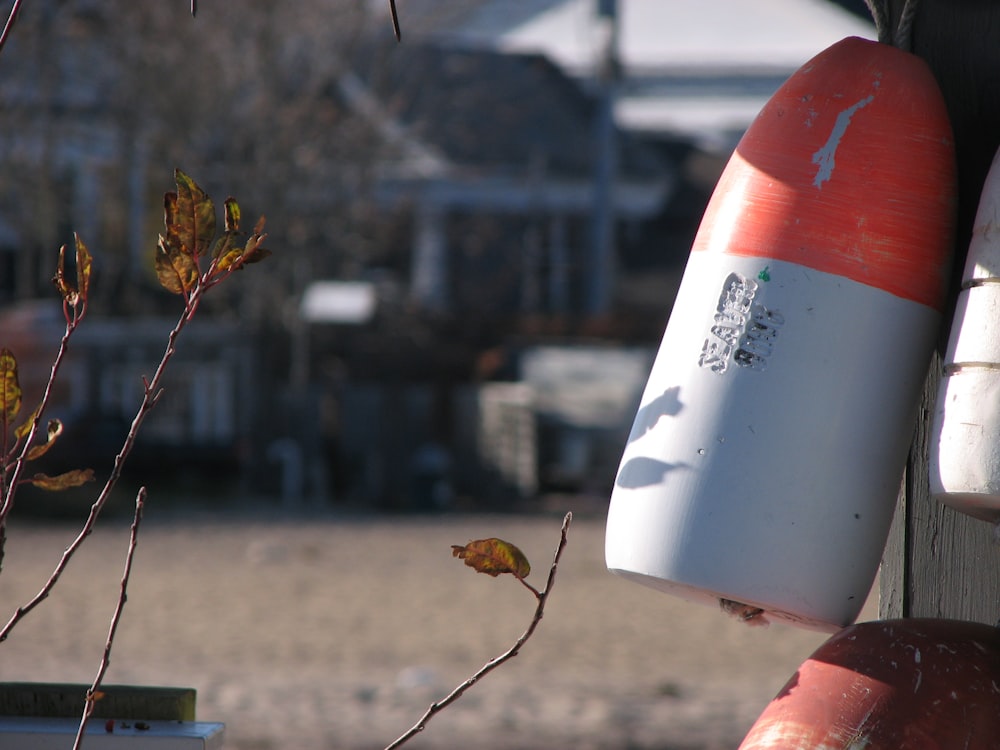 a red and white buoy sitting next to a tree