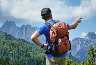 a man with a backpack pointing at the mountains