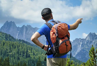 a man with a backpack pointing at the mountains
