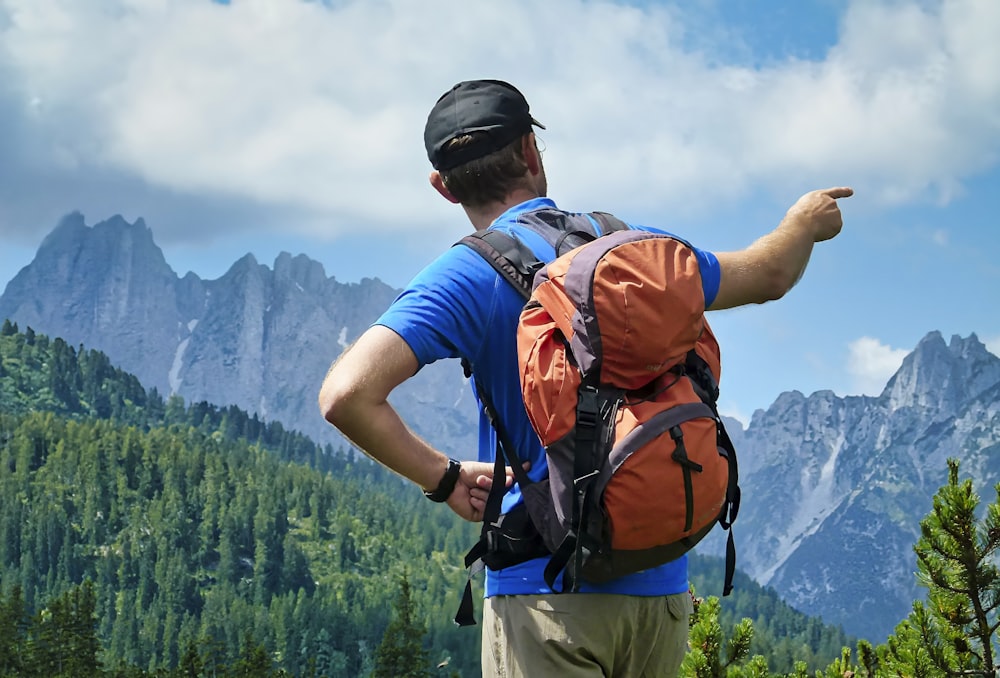 a man with a backpack pointing at the mountains