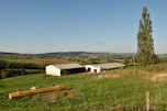 A rural landscape with rolling hills dotted with farm buildings under blue sky.