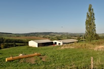 A rural hospital building surrounded by open fields under a bright blue sky.