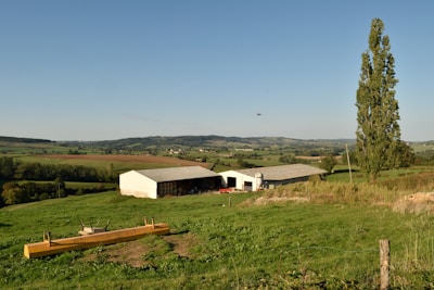 A rural hospital building surrounded by open fields under a bright blue sky.