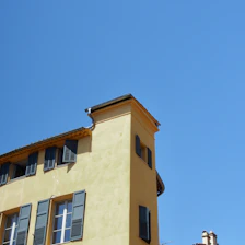 Benny and his team smiling in front of a house with clean gutters on a sunny day.