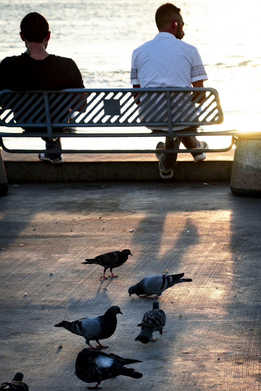 a couple of people sitting on a bench next to a body of water