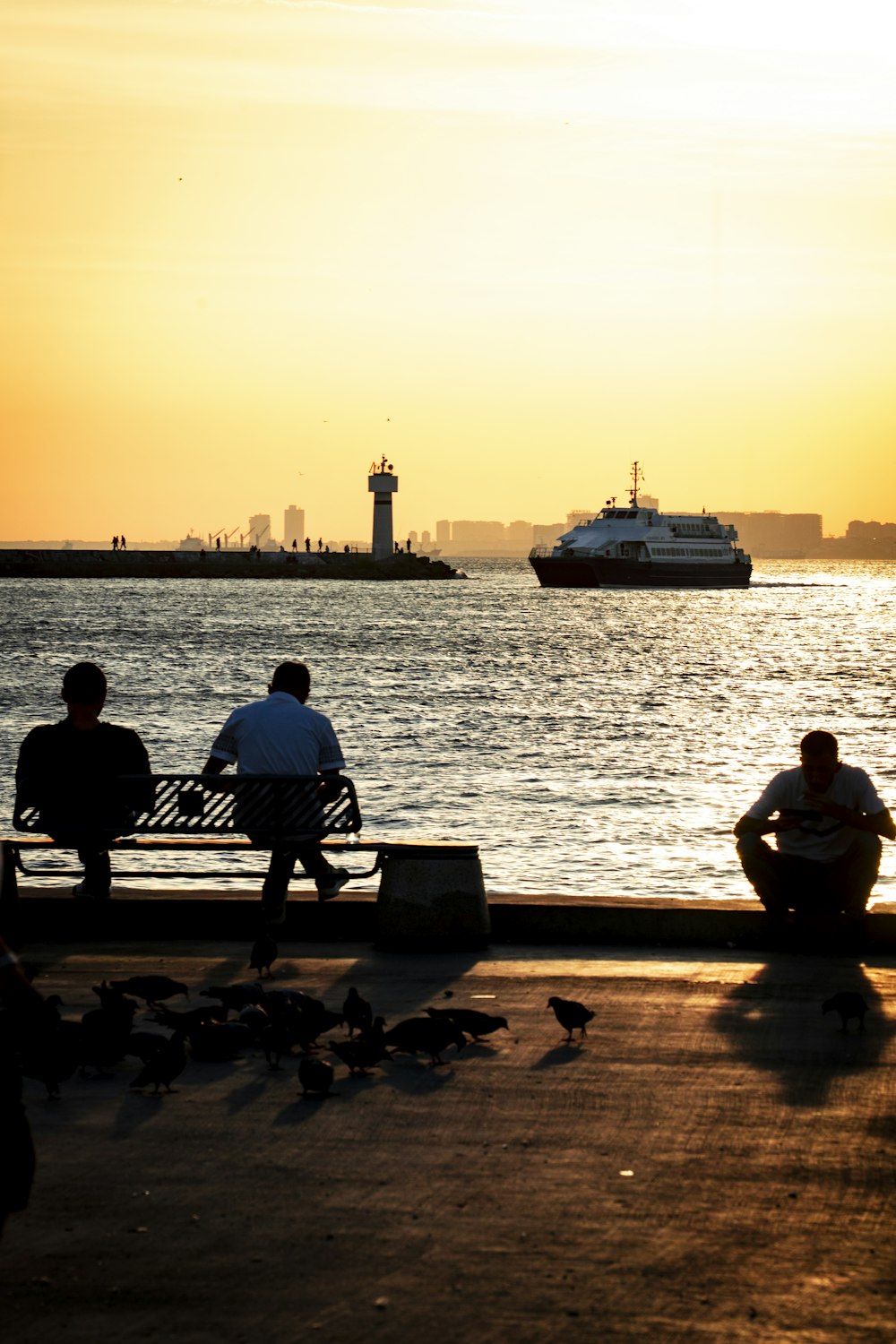 a couple of people sitting on a bench near the water