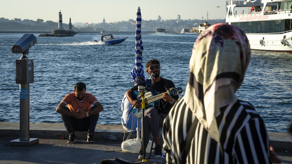 a group of people sitting next to a body of water