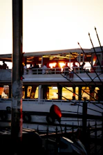 Golden hour shot of a family laughing together on a sunlit boat deck, sails softly blurred in the background.