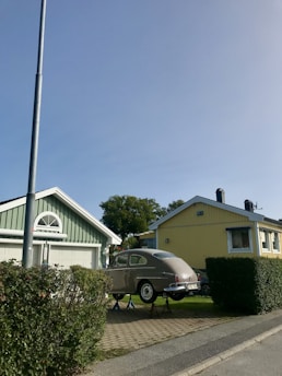 Flatbed tow truck transporting a classic car in a residential Houston neighborhood.