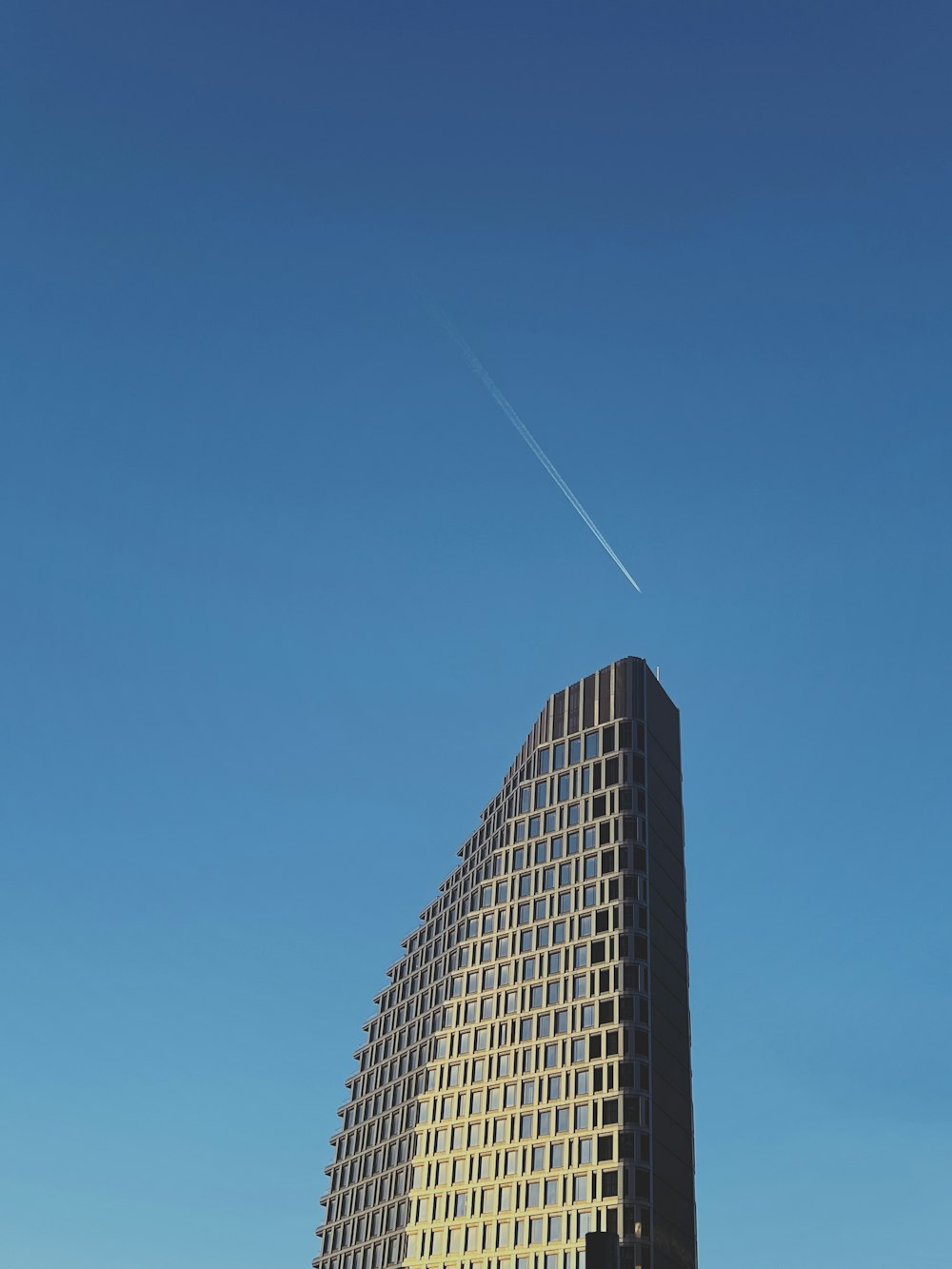 Un edificio molto alto con un aereo che vola nel cielo