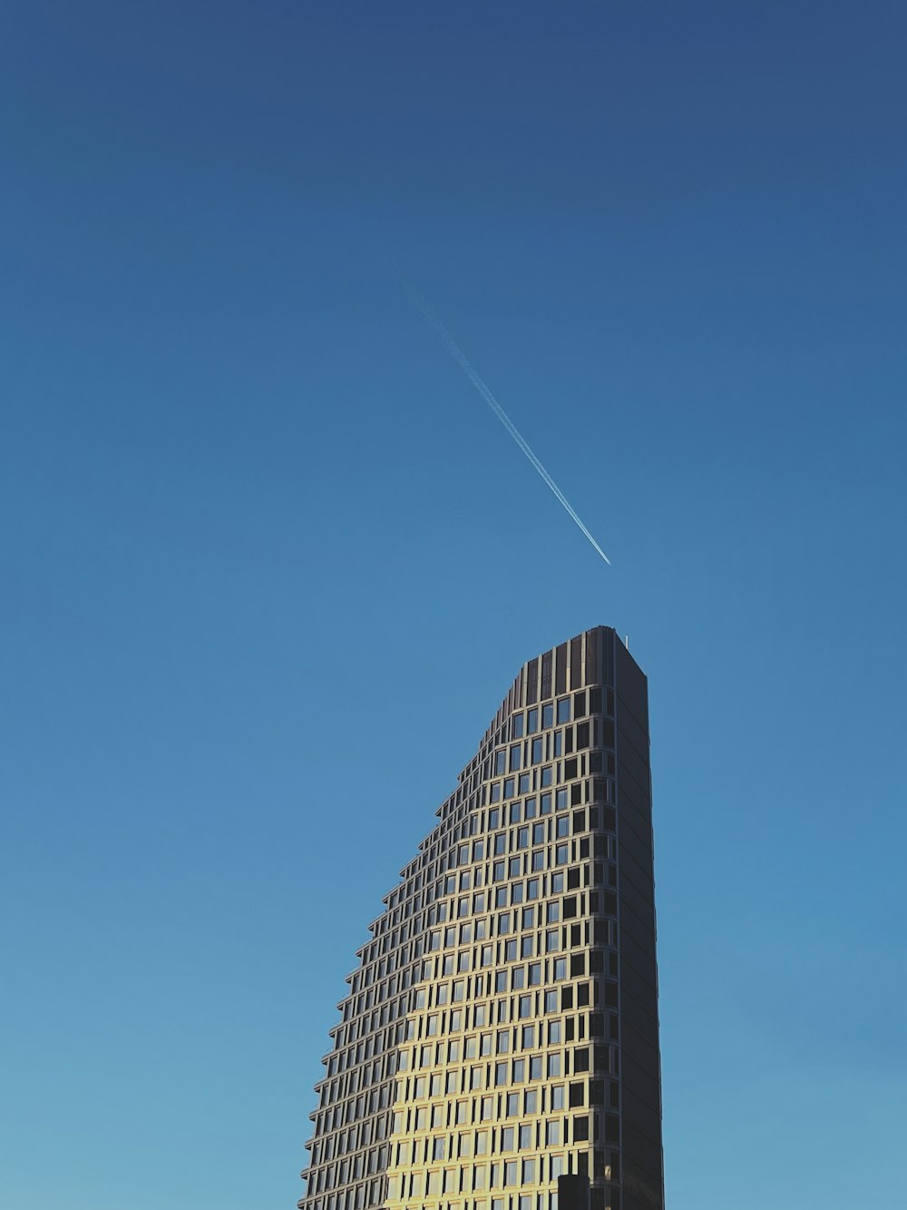 a very tall building with a plane flying in the sky