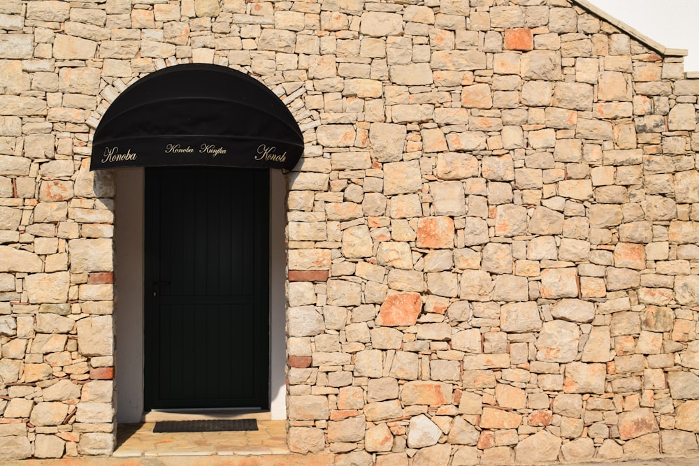 a stone building with a black door and arched window