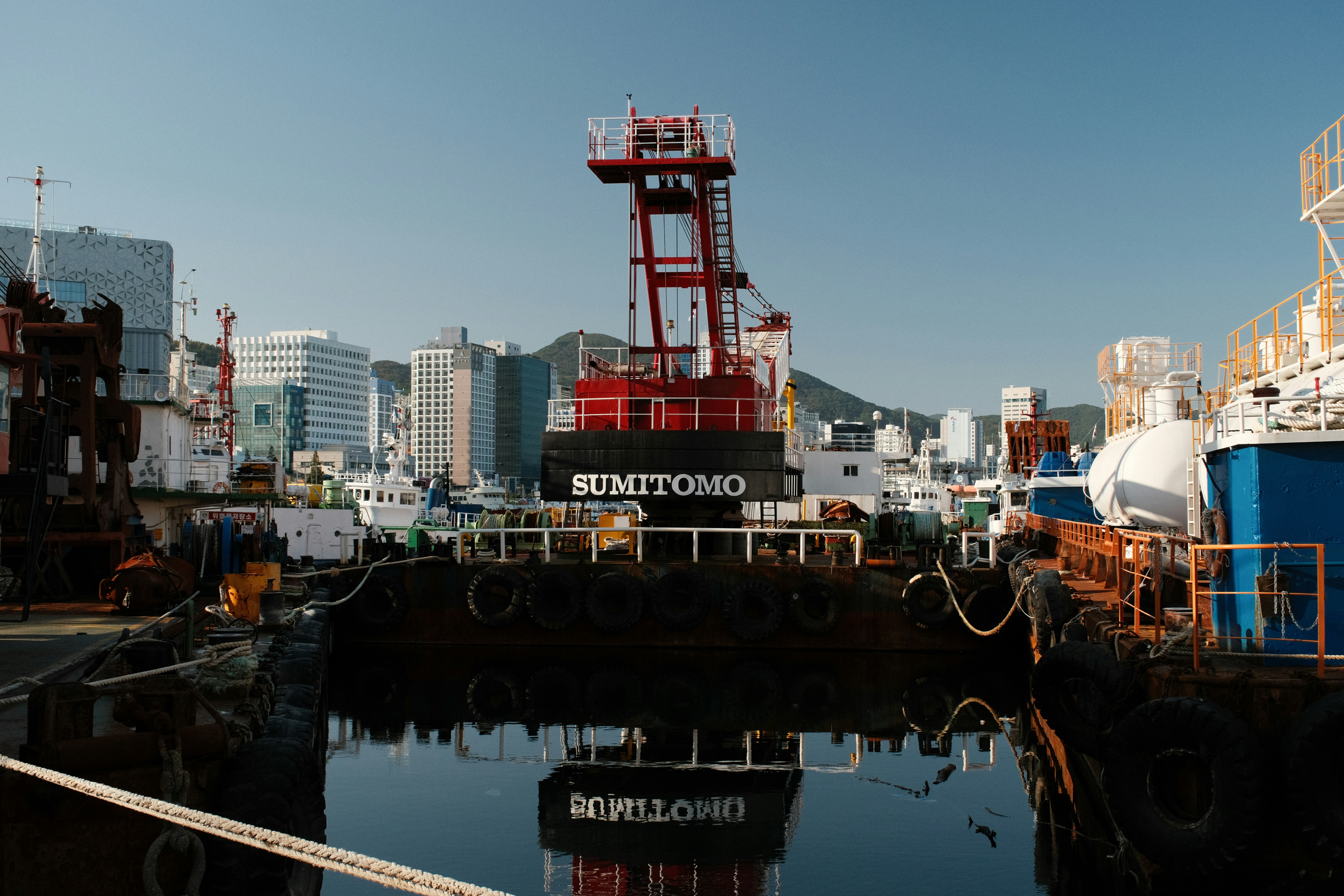 Ein Schlepper, der in einem Hafen angedockt ist, mit einer Stadt im Hintergrund