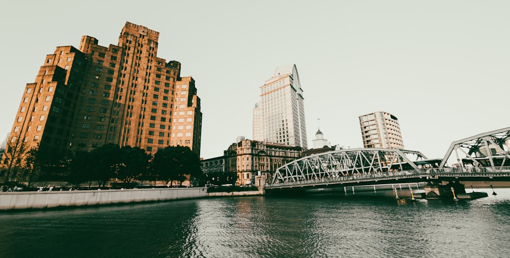 a bridge over a body of water with tall buildings in the background