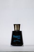 A black perfume bottle with a shiny gold cap. The label reads 'Bugatti Black' along with details about the volume and type of product in blue text.