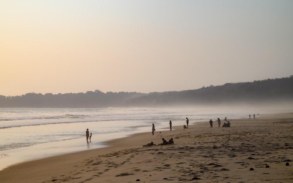 um grupo de pessoas em pé em cima de uma praia de areia