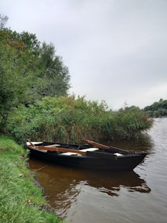 A small boat anchored near a lush riverside, ready for a day of fishing.