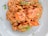 A plate of shrimp risotto garnished with fresh herbs and crispy chips. The dish has a creamy texture with visible pieces of shrimp and seasonings.