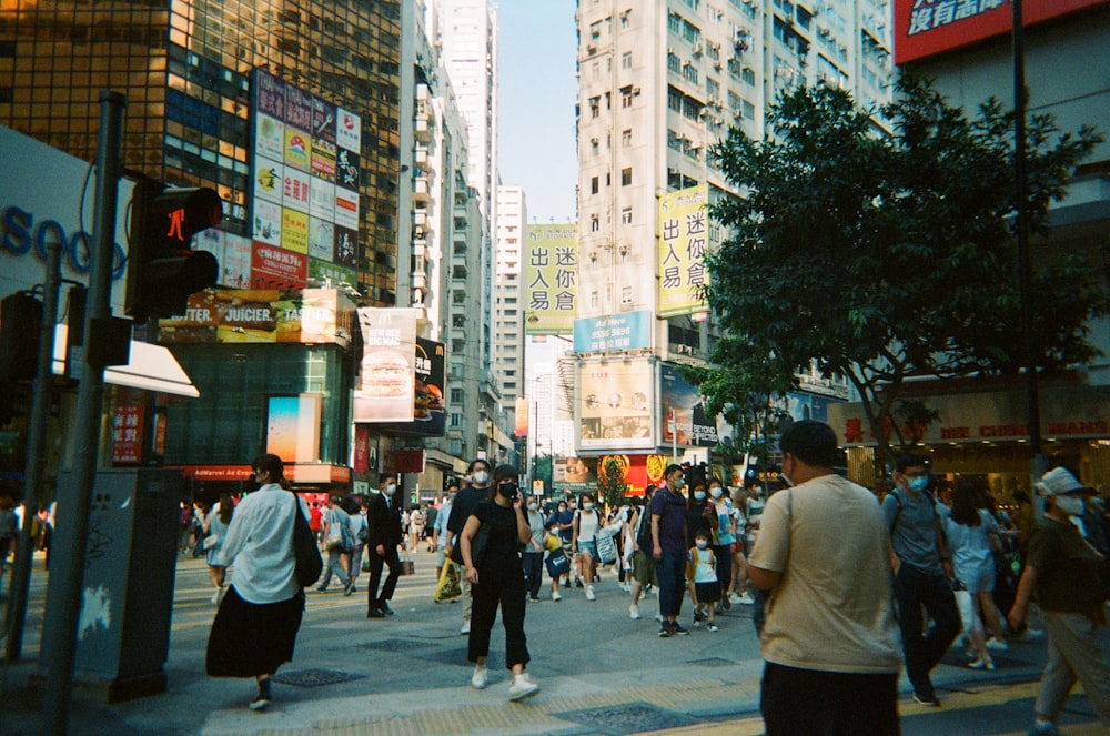 eine Menschenmenge, die eine Straße neben hohen Gebäuden entlanggeht