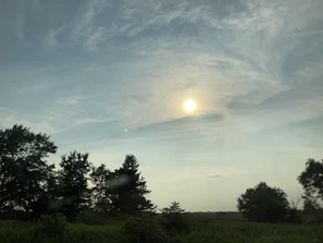 A serene morning sky with soft clouds over a quiet landscape.